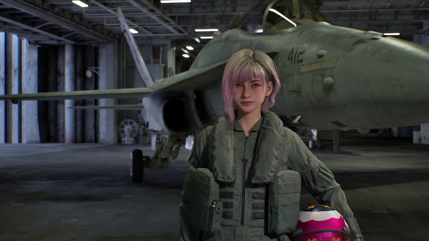 A pilot with pink hair stands in a hangar in front of a gray fighter jet, holding her helmet.