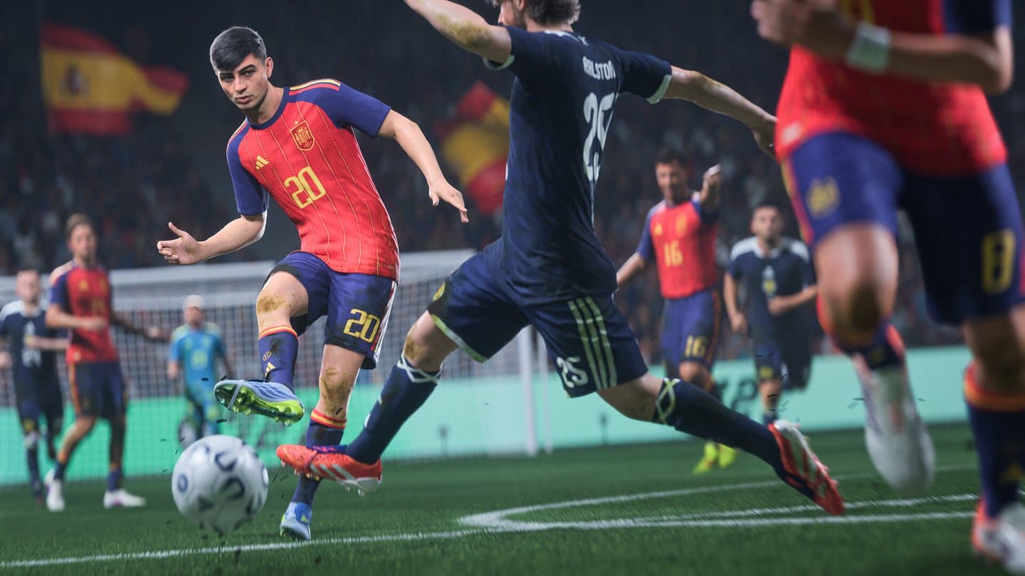 A Spain player in red shoots past a defender in navy, in front of a stand full of Spanish flags.
