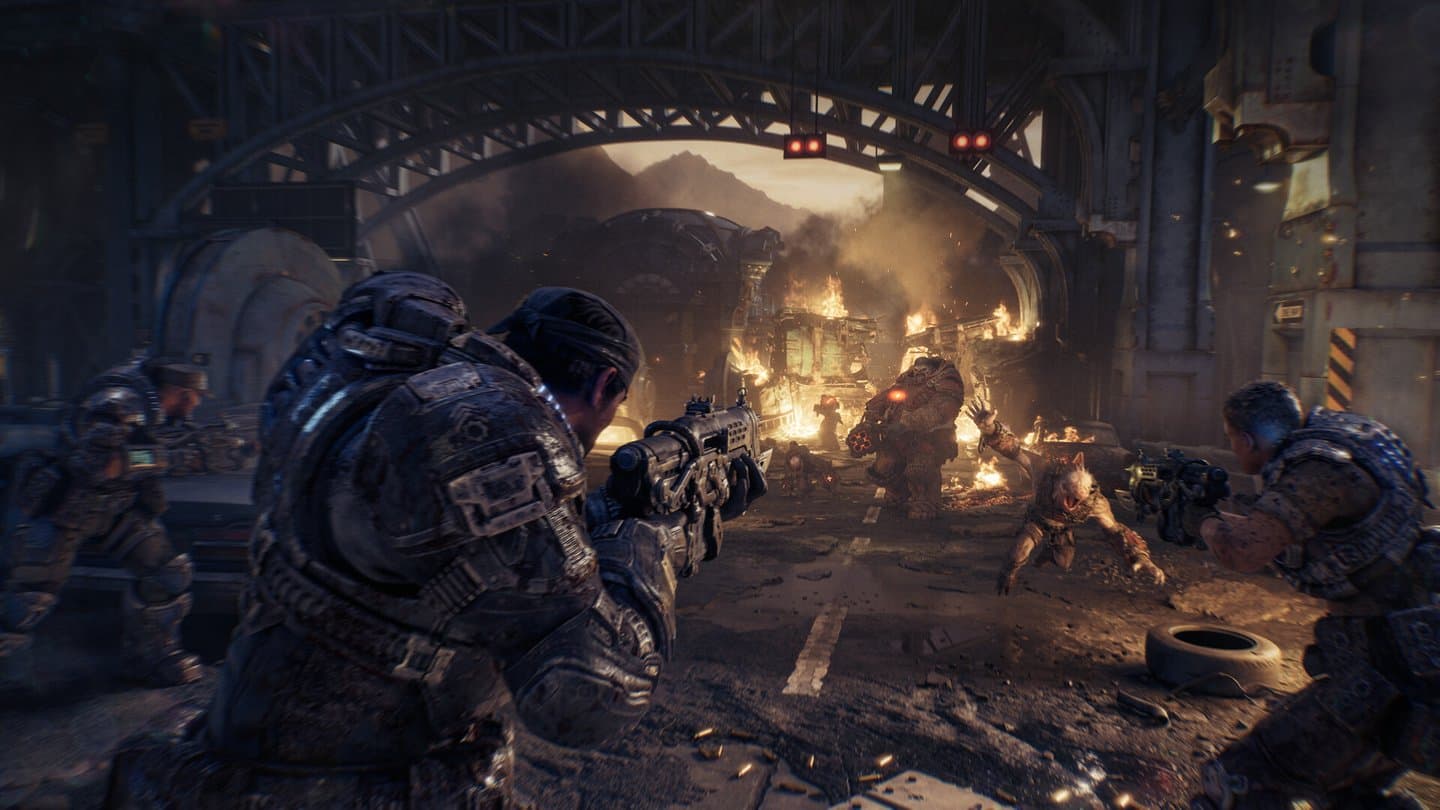 Two soldiers in heavy armor fire at creatures across a burning street under a steel bridge.